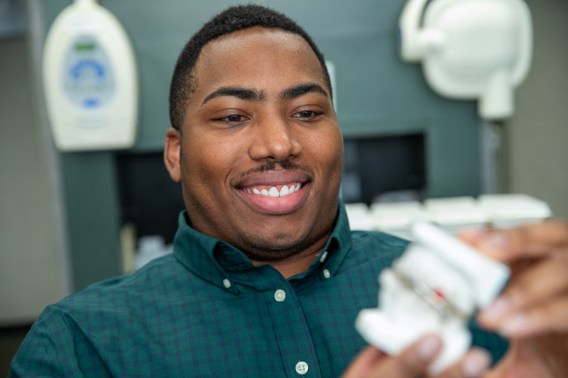 dental implant patient holding teeth model