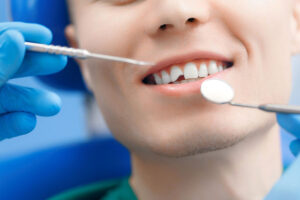 Dentist examining a patient's teeth with dental mirror and probe during a routine check-up.